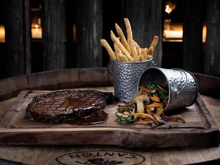 Steak, fries and veggies displayed on a wooden cutting board