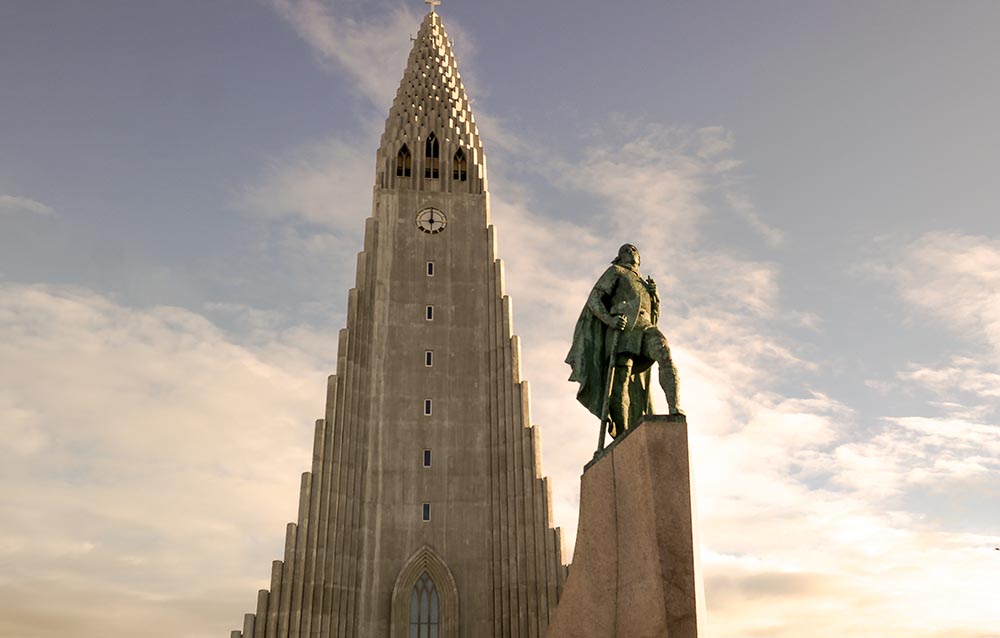 Looking up at a beautiful church with a statue standing in front.