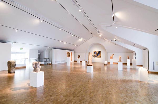 Indoor photo of the modern National Gallery of Art with Sculptures spread around the room.