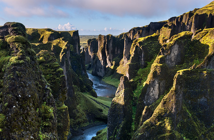 A long view of a long and deep canyone with rock and grass.