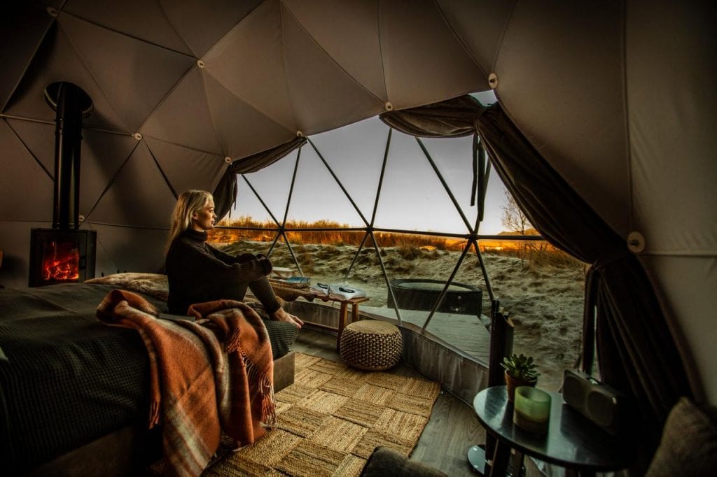 woman sitting in igloo hotel looking out window